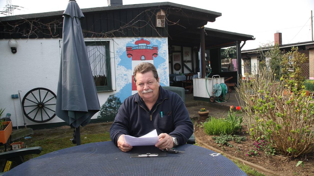Hans Gilson sitzt an einem Tisch in einem Kleingarten.