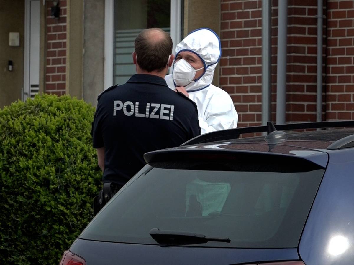 Ein Polizist und ein Beamter der Spurensicherung unterhalten sich an einem Tatort.