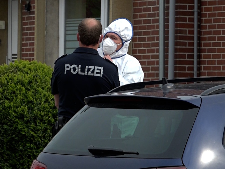 Ein Polizist und ein Beamter der Spurensicherung unterhalten sich an einem Tatort.