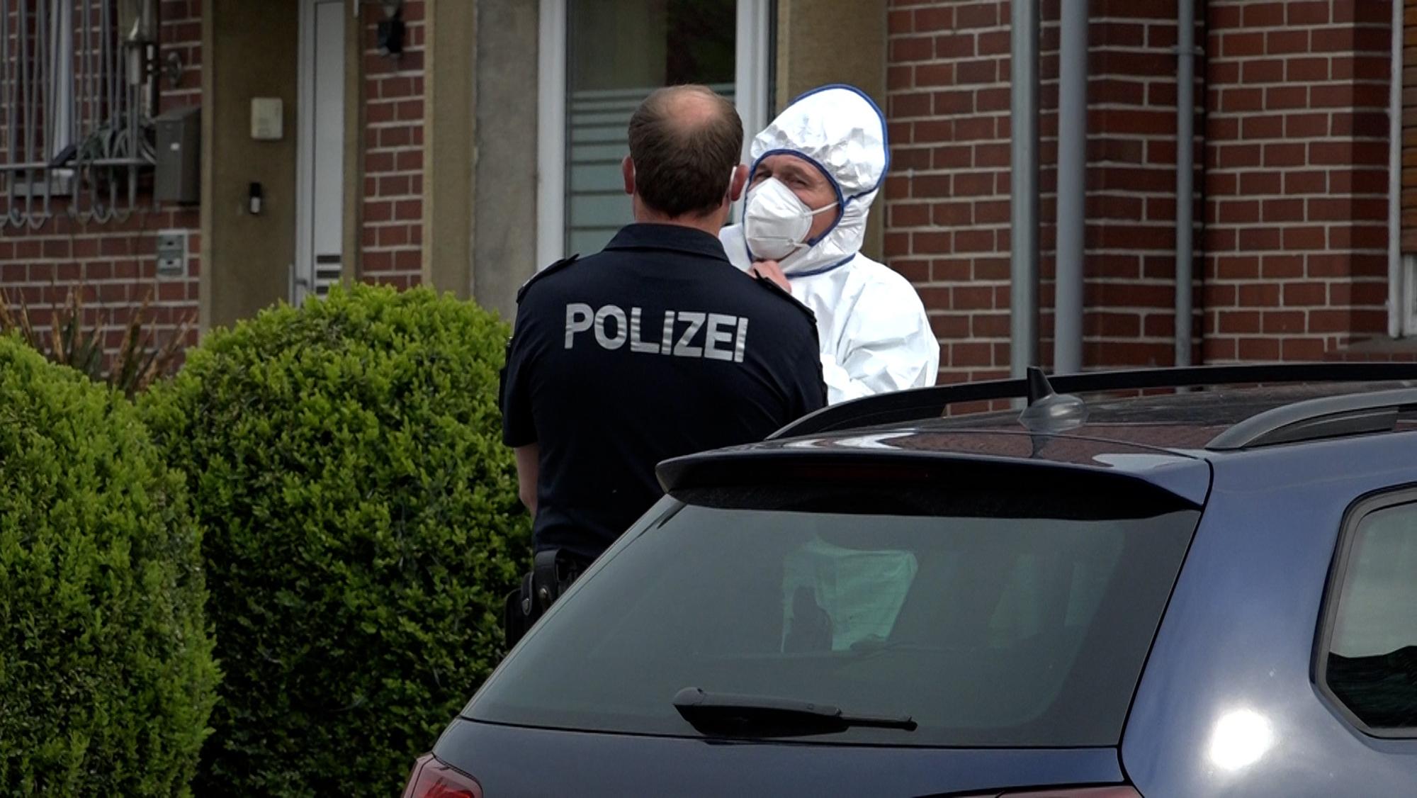Ein Polizist und ein Beamter der Spurensicherung unterhalten sich an einem Tatort.
