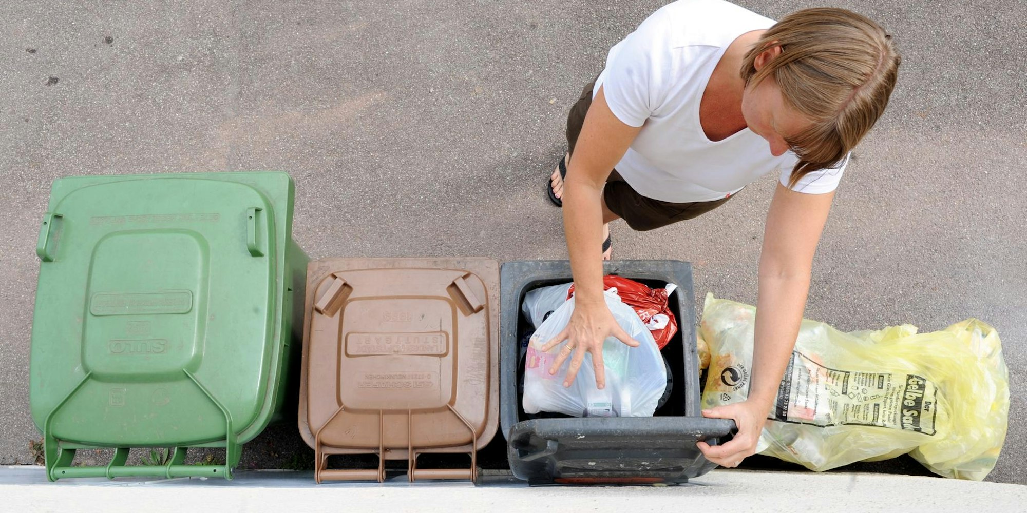 Frau_schmeißt_Müll_in_eine_Mülltonne