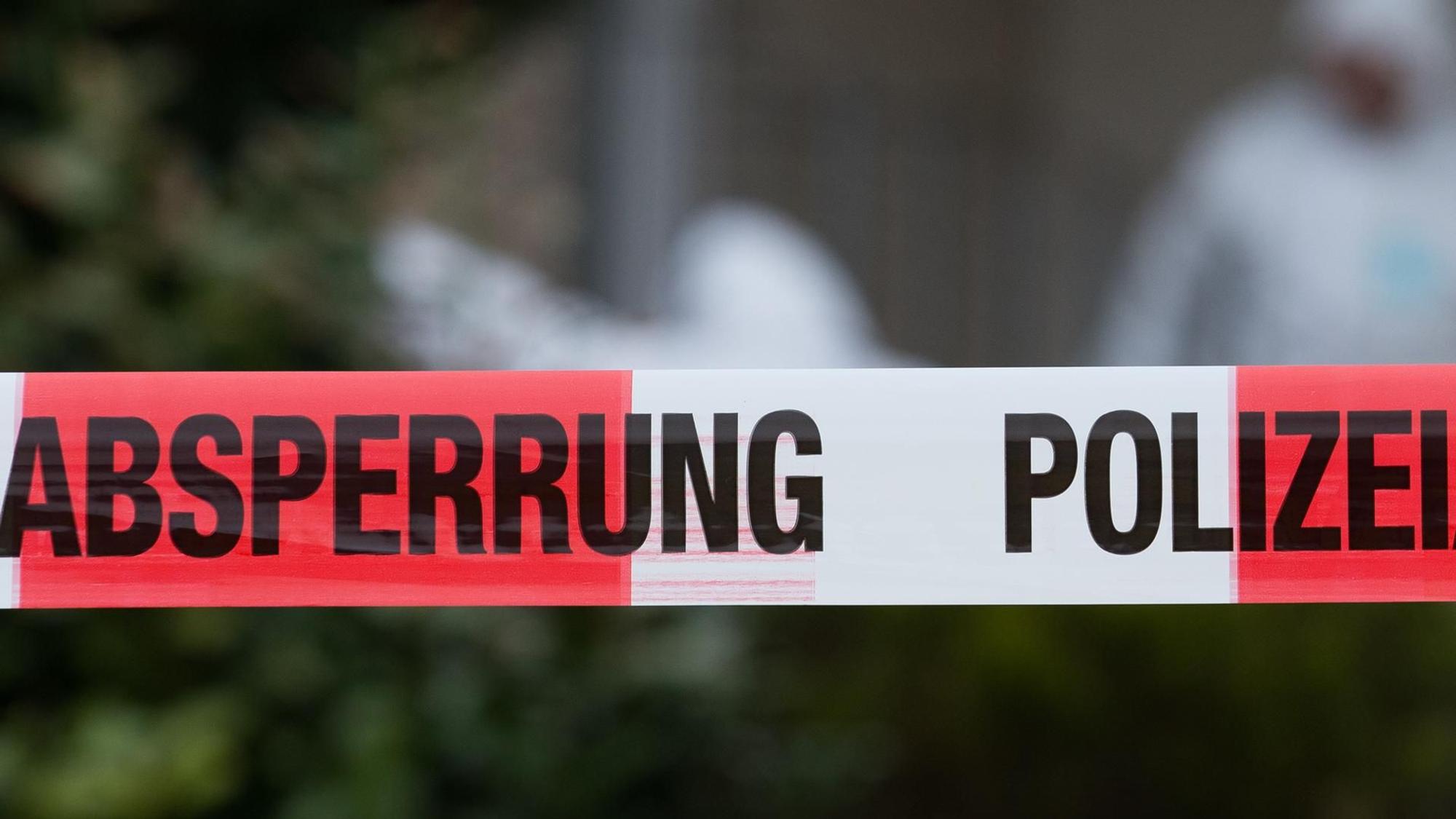 Flatterband der Polizei, im Hintergrund Ermittler der Spurensicherung