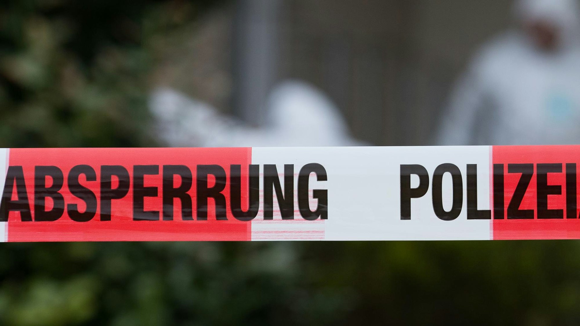 Flatterband der Polizei, im Hintergrund Ermittler der Spurensicherung