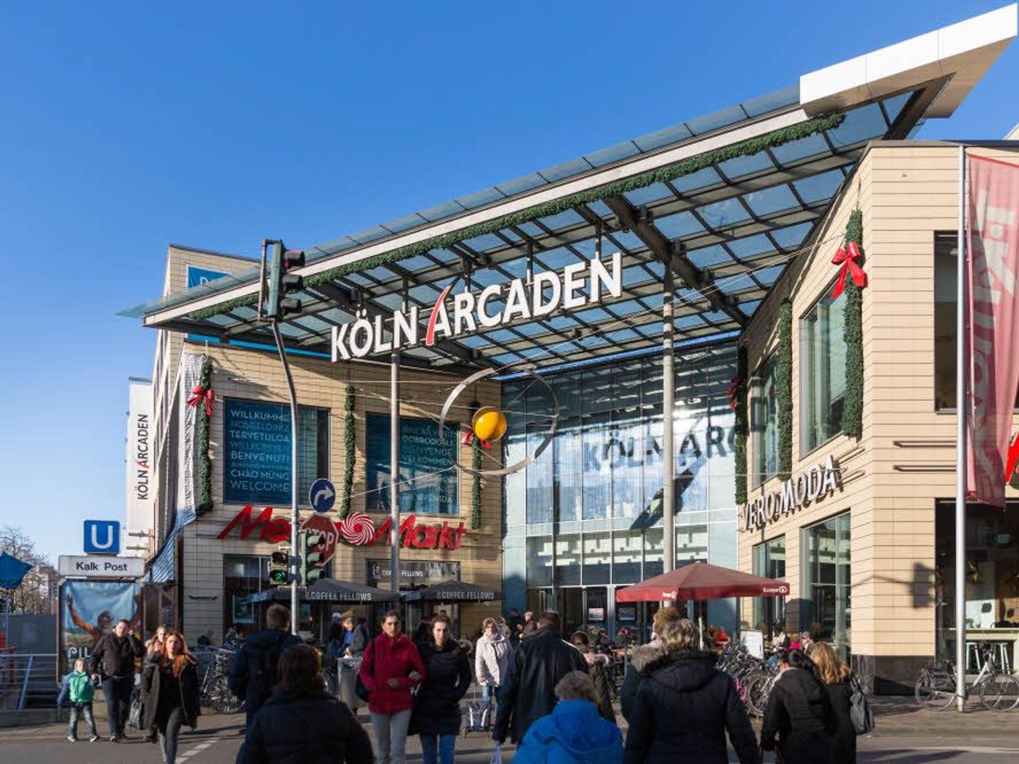 Menschen strömen auf den Eingang der Köln Arcaden zu.