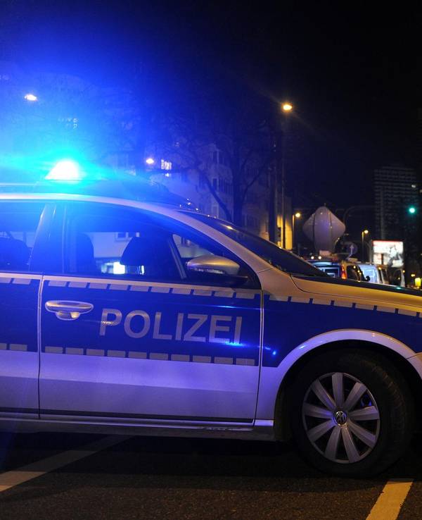 Ein Streifenwagen der Polizei ist abends auf einer Straße unterwegs.