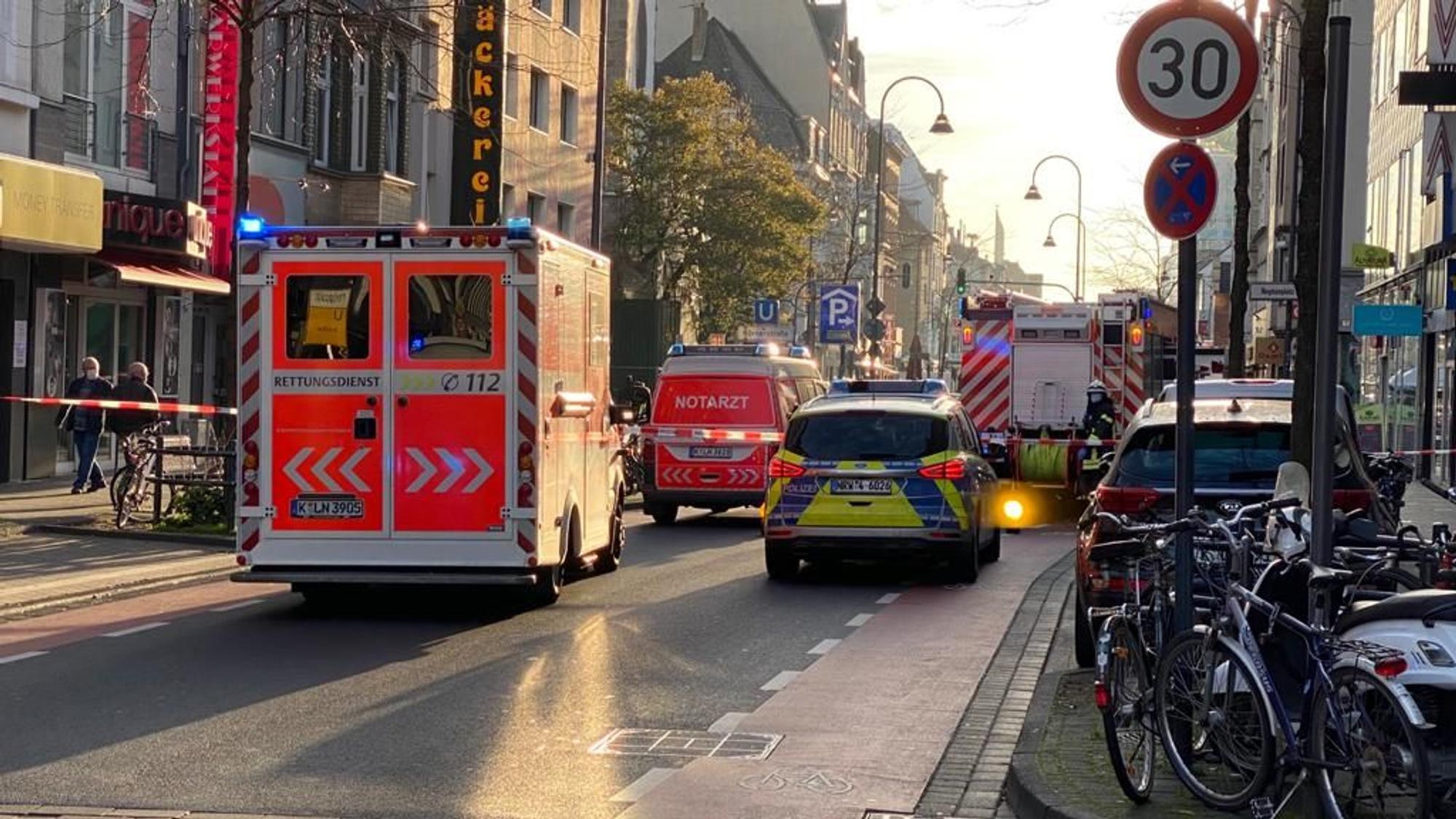Einsatzfahrzeuge von Rettungsdienst, Polizei und Feuerwehr stehen auf der Straße, deren Fahrbahn mit Flatterband abgesperrt ist.