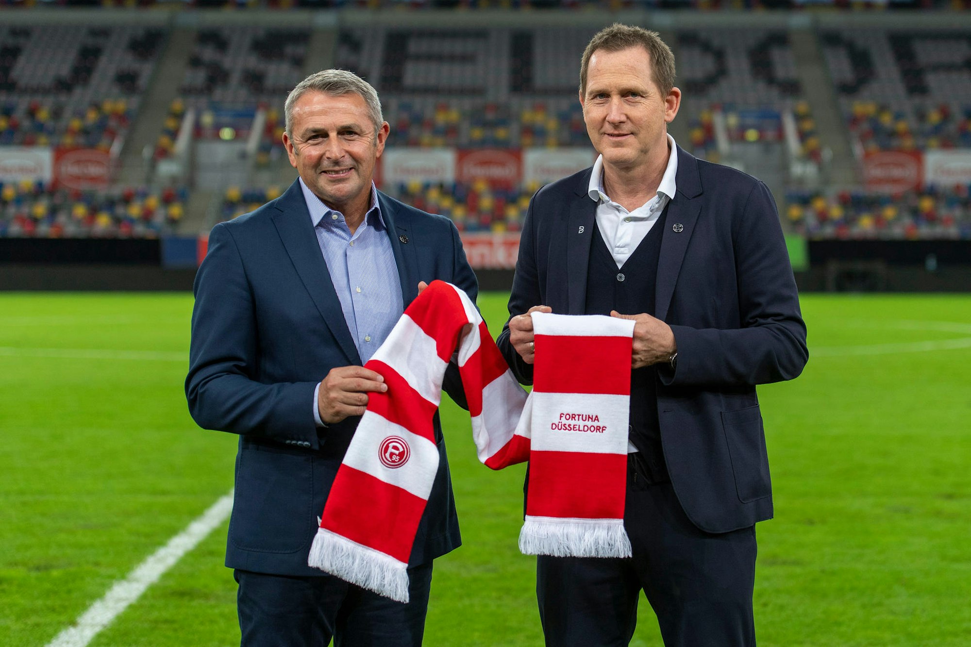 Uwe Klein (r.) und Klaus Allofs posieren mit dem Schal von Fortuna Düsseldorf.