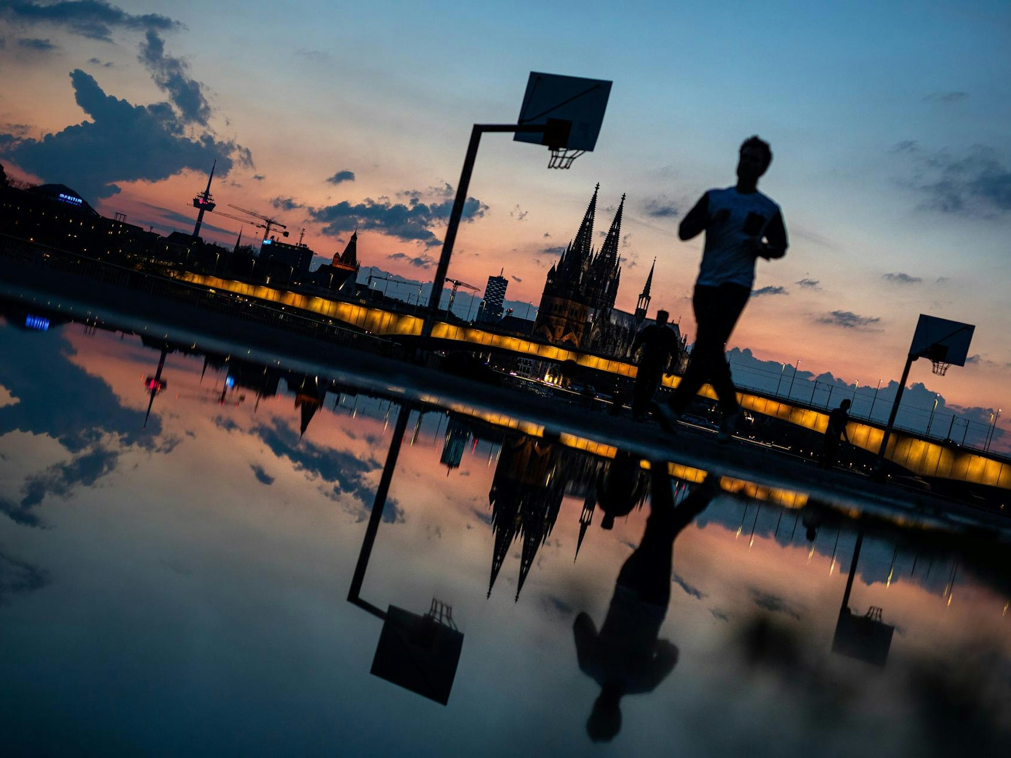 Ein Mann läuft am Rheinufer in Köln entlang.