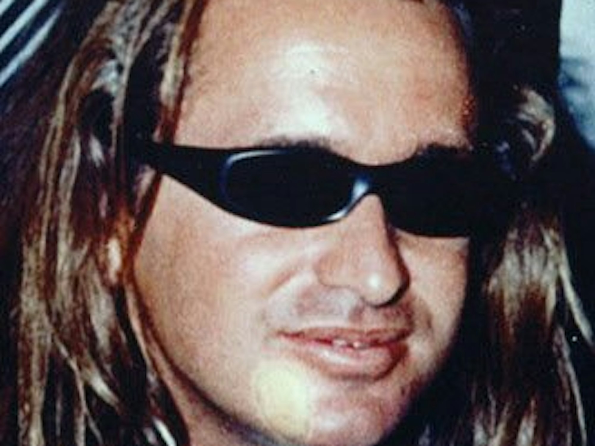 Ein Mann mit langen Haaren trägt eine Sonnenbrille.