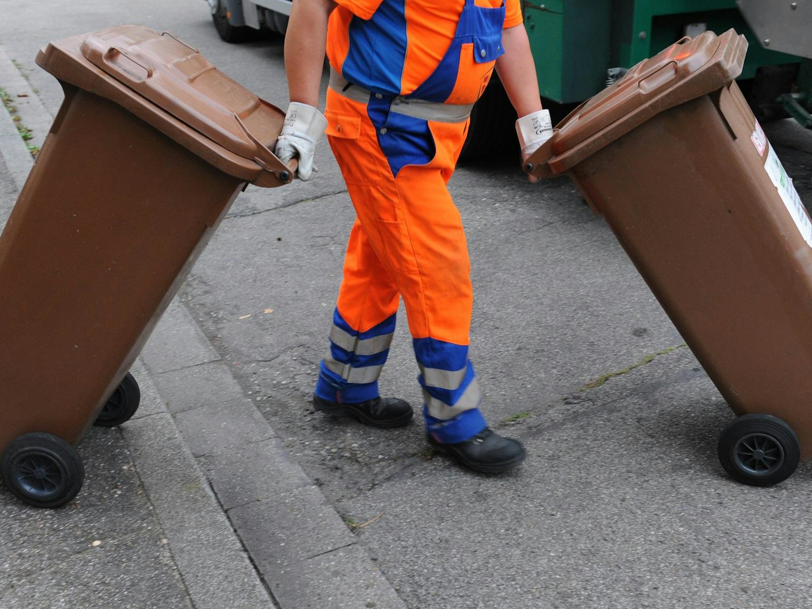 Ein Mitarbeiter der Müllabfuhr mit zwei Bio-Mülltonnen.