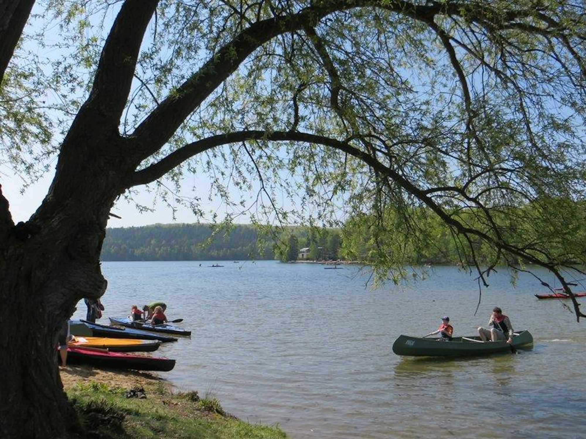 Menschen paddeln in Kanus über einen See