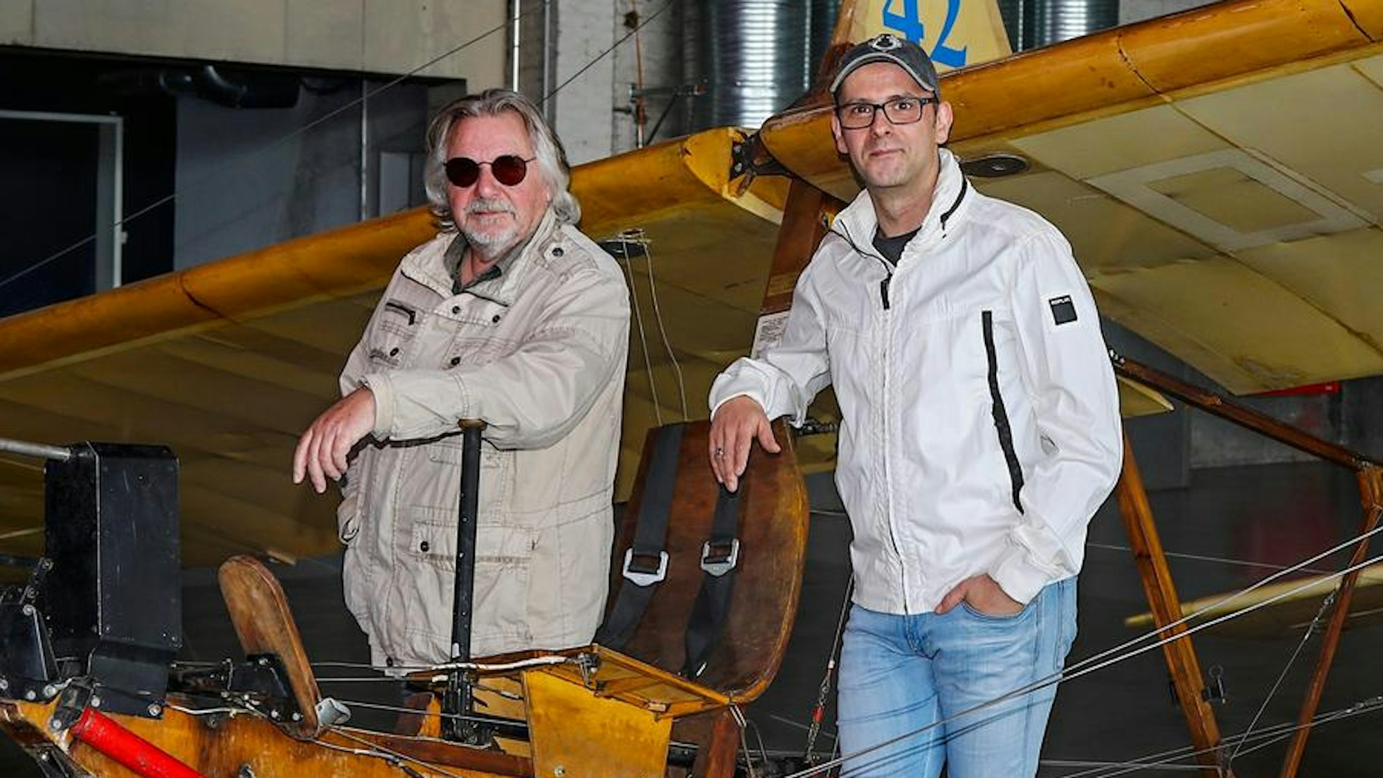 Tommy Engel steht neben Marc Metzger an einem alten Holzflugzeug
