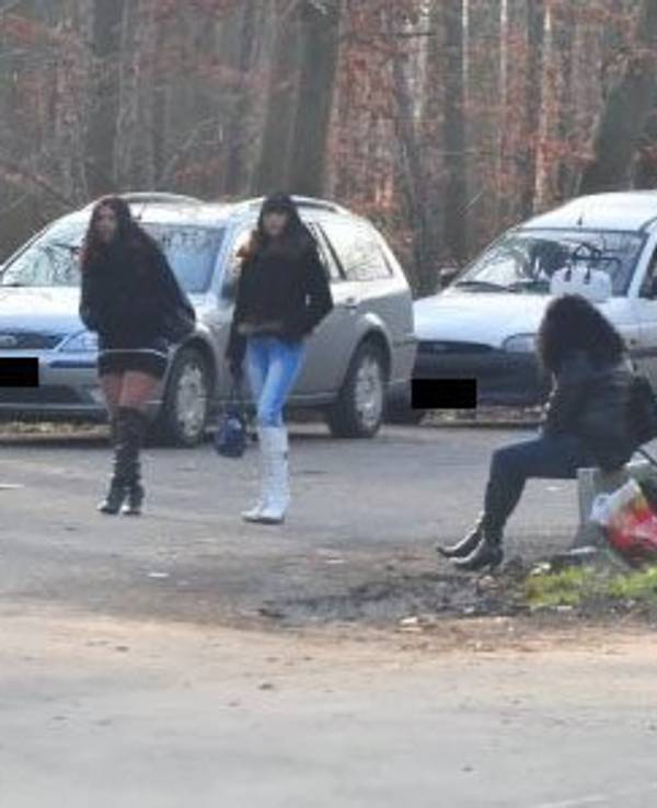 Eine Frau sitzt am Straßenstrich, zwei weitere gehen an ihr vorbei.