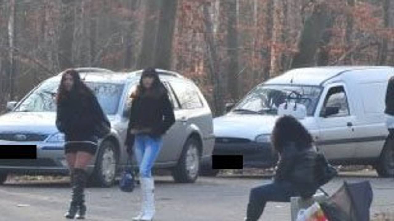 Eine Frau sitzt am Straßenstrich, zwei weitere gehen an ihr vorbei.