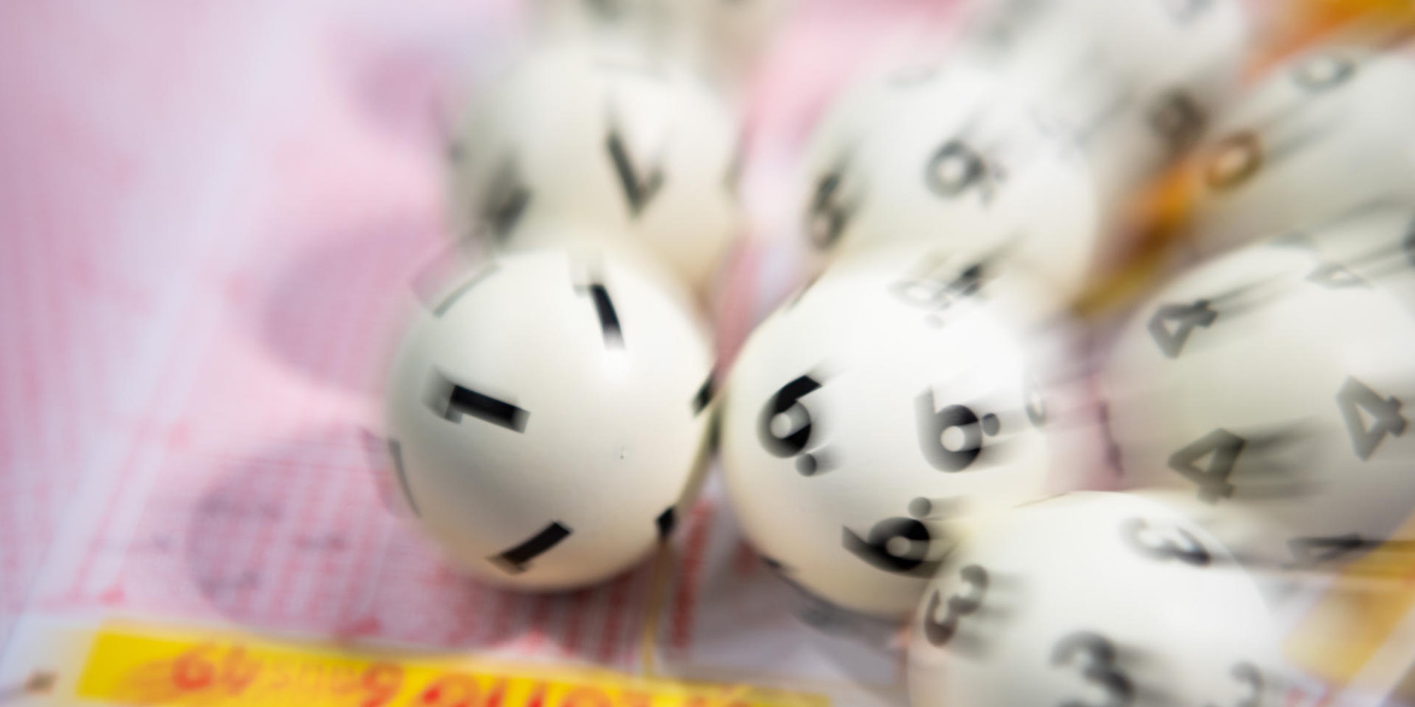 Lottokugeln liegen auf Tippschein