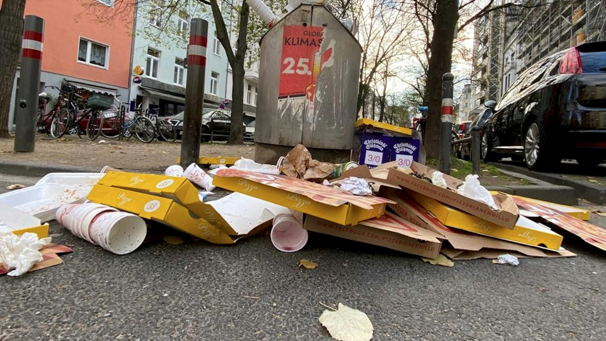 Müll, darunter Fastfood-Verpackungen und Getränkebecher, liegt auf der Straße.