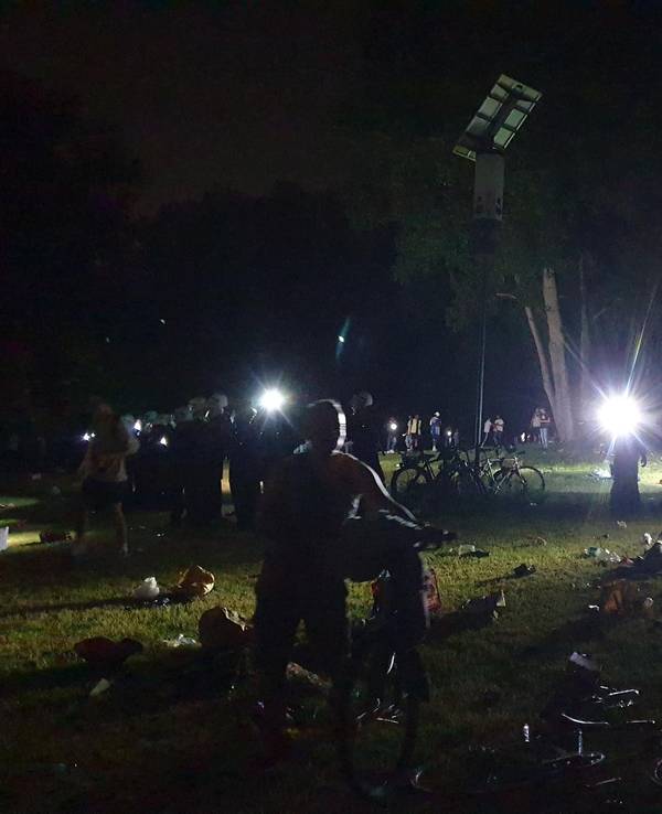 Kölner Polizisten leuchten mit Taschenlampen über die Wiese am Aachener Weiher