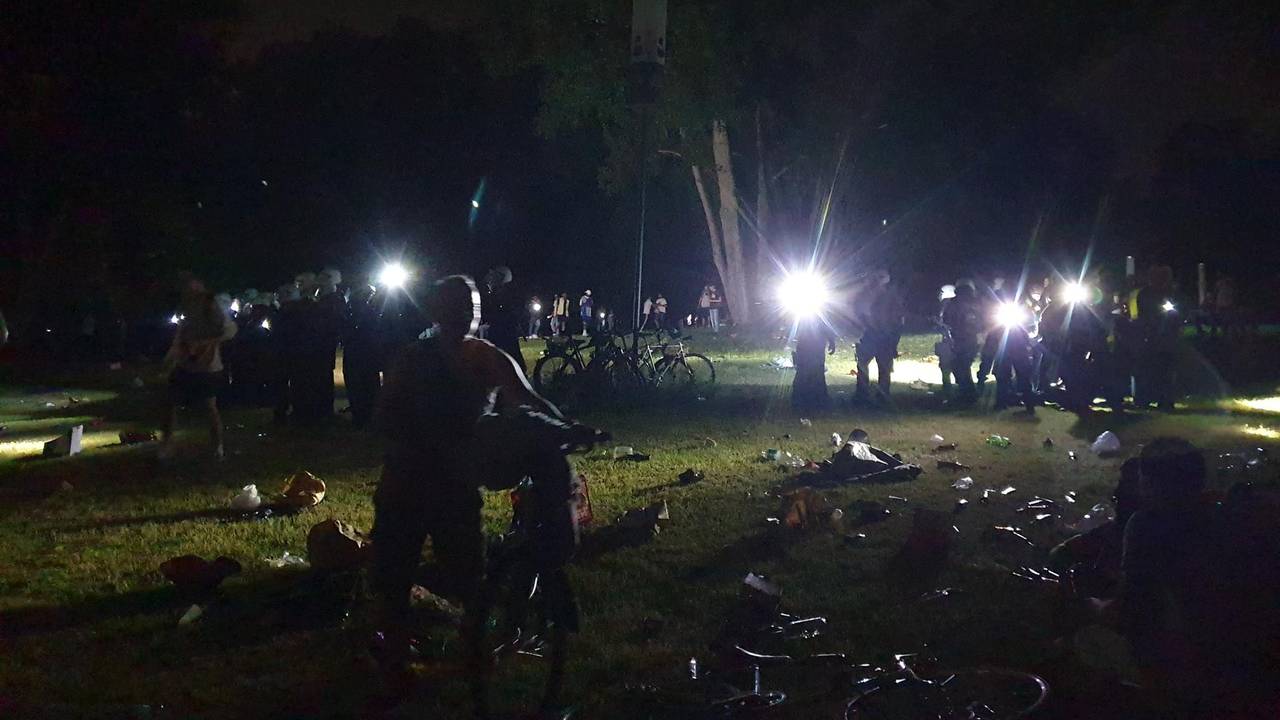 Kölner Polizisten leuchten mit Taschenlampen über die Wiese am Aachener Weiher