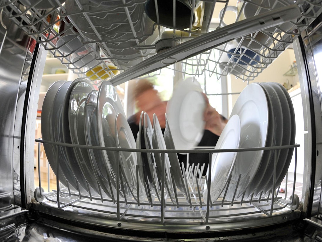 Ein Mann räumt die Spülmaschine ein.