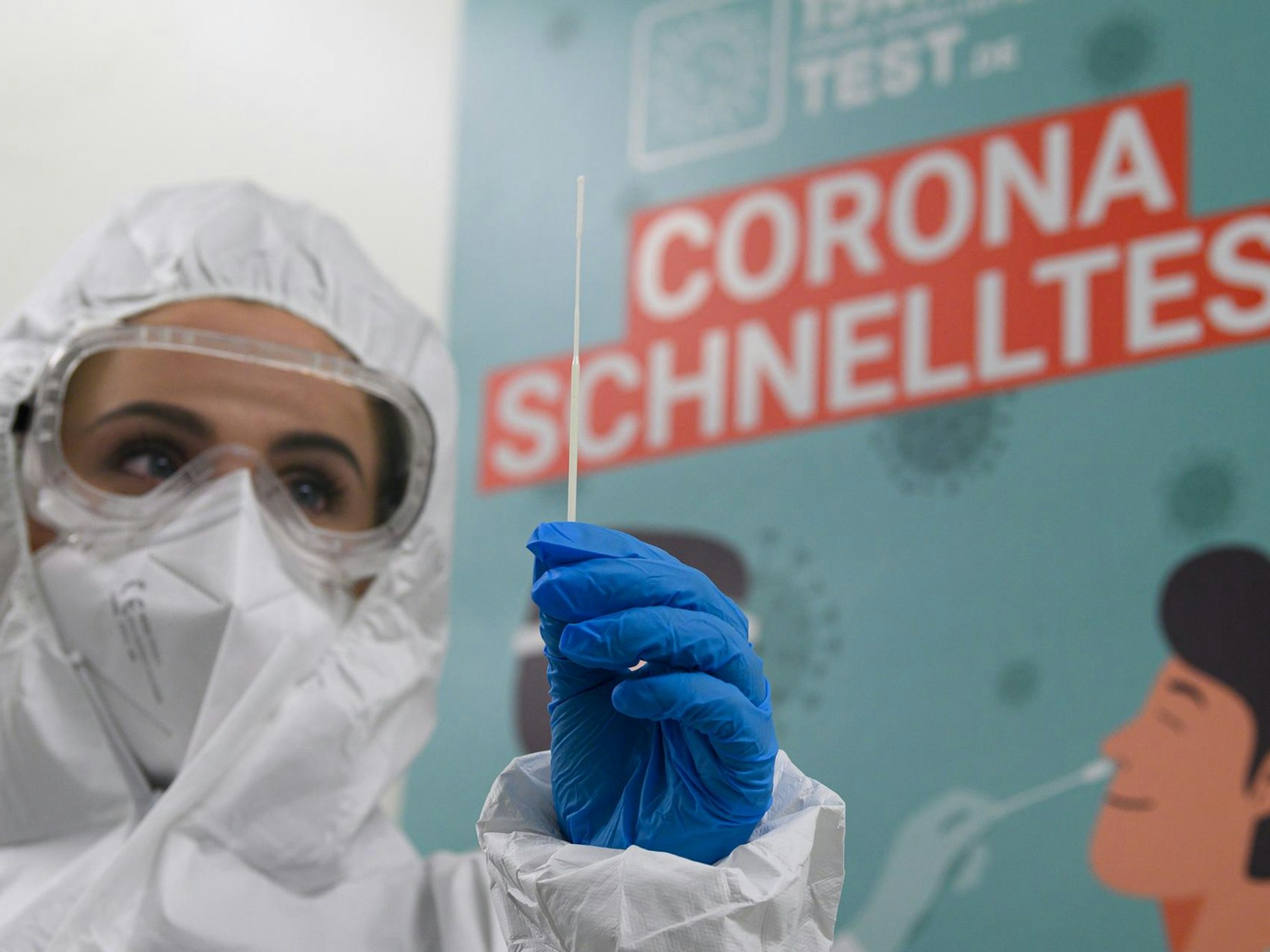 Eine Mitarbeiterin in Schutzanzug bereitet einen Corona-Test vor.