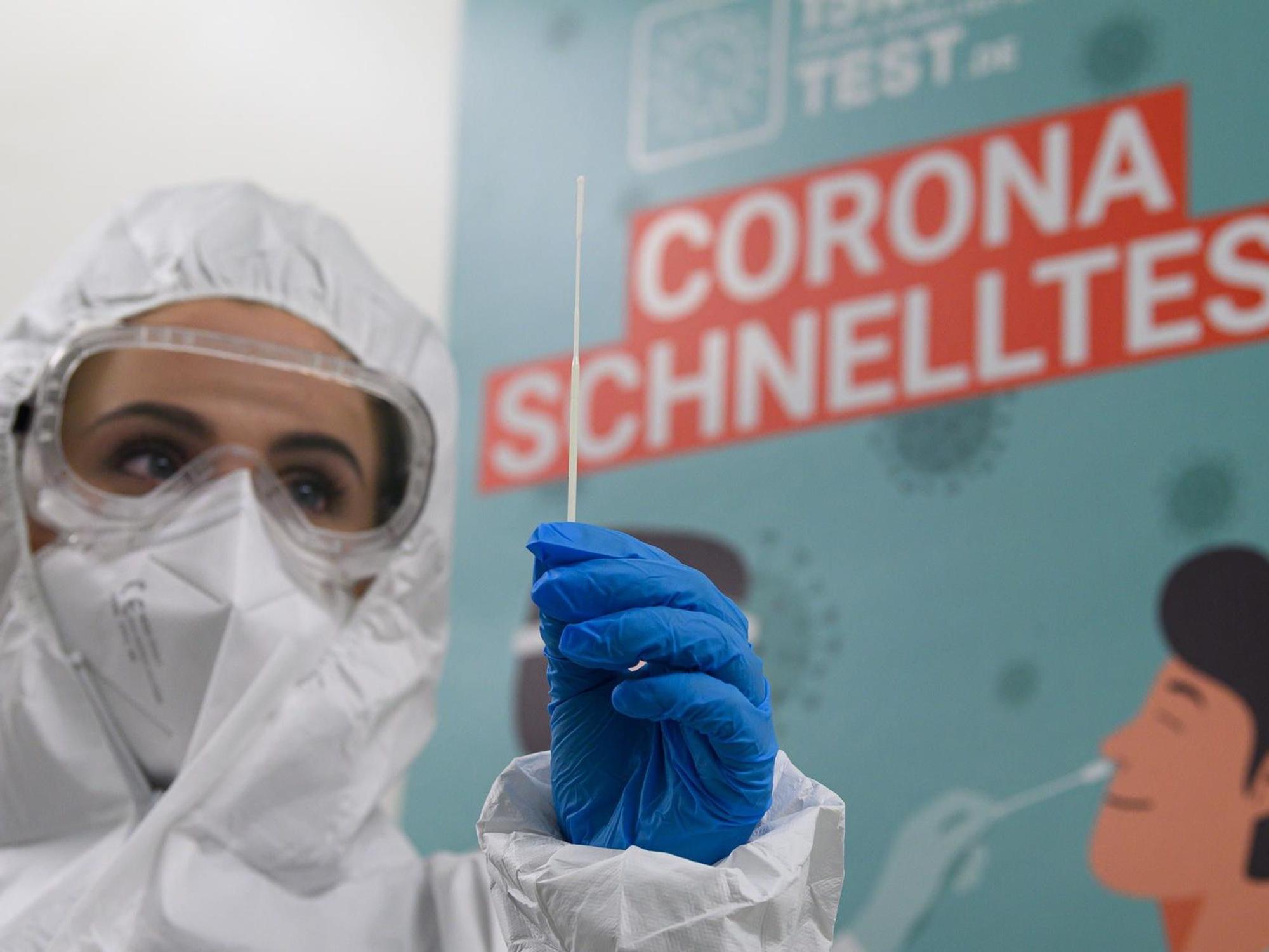 Eine Mitarbeiterin in Schutzanzug bereitet einen Corona-Test vor.