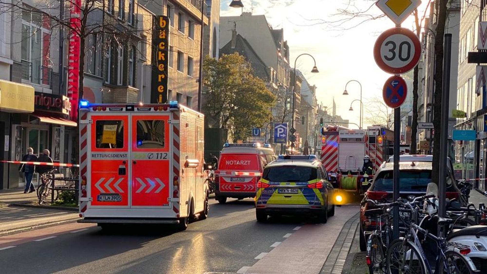 Die Polizei hat die Fahrbahn einer Straße abgesperrt, mehrere Einsatzfahrzeuge von Polizei, Rettungsdienst und Feuerwehr sind vor Ort.