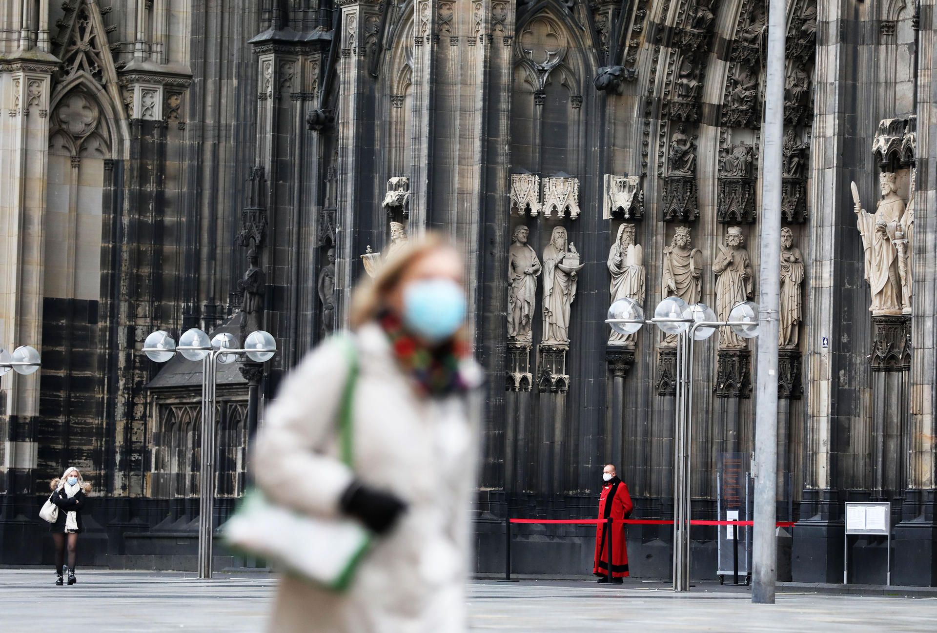 Eine Frau mit Corona-Maske vor dem Kölner Dom