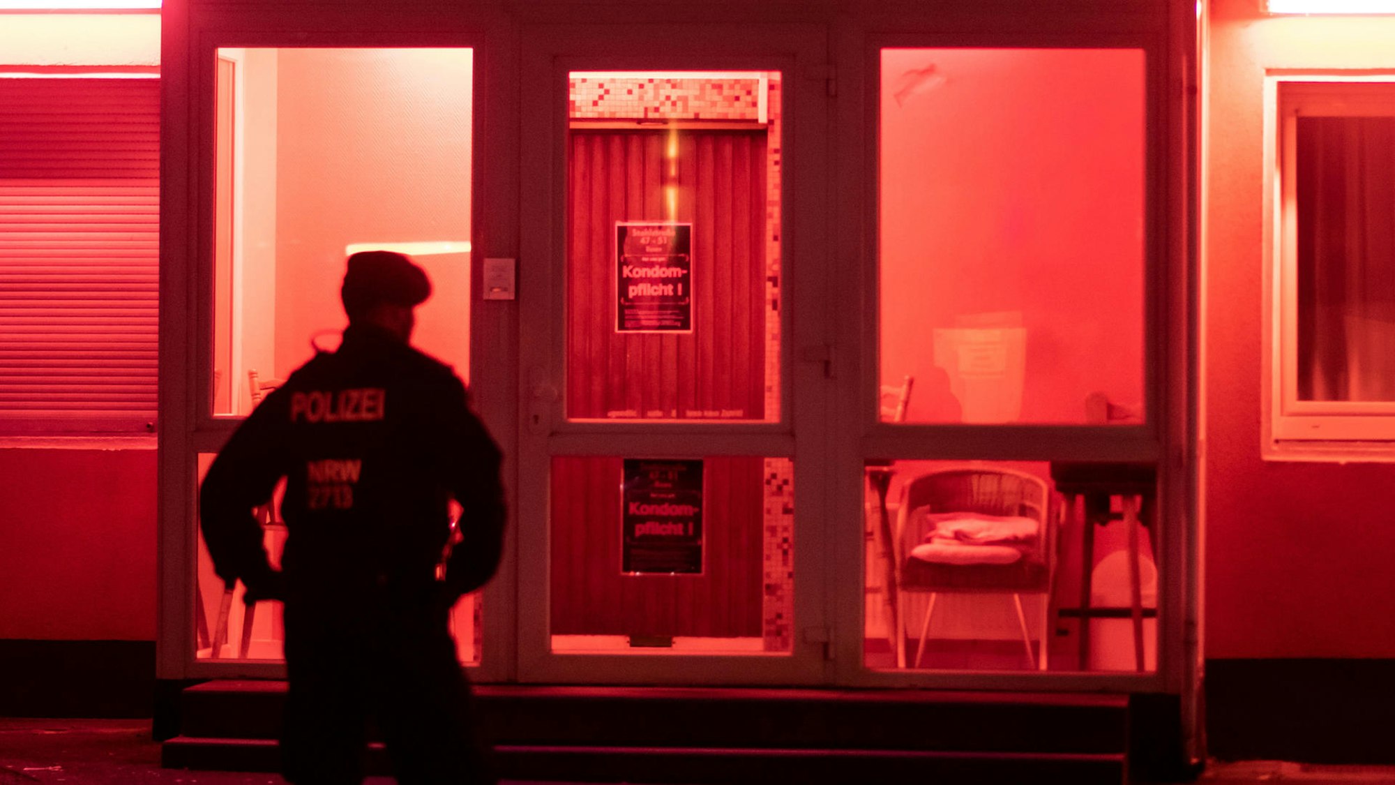 Ein Polizist steht bei einem Einsatz vor einem Bordell.