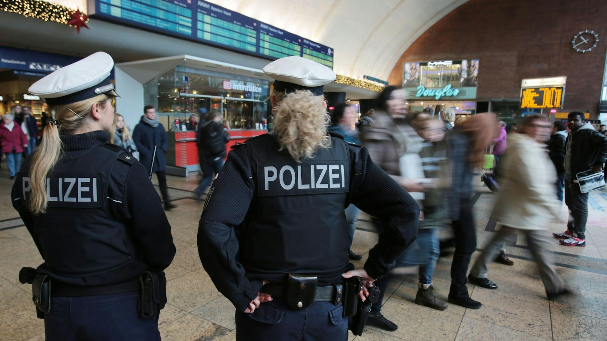 Polizistinnen kontrollieren im Kölner Hauptbahnhof Menschen.