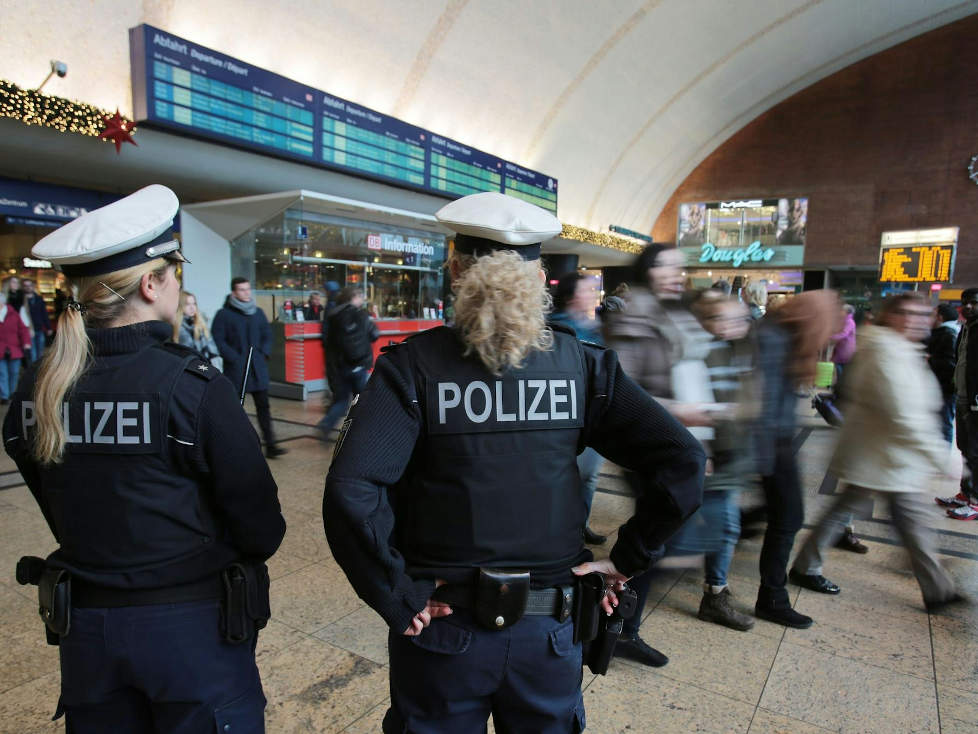 Polizistinnen kontrollieren im Kölner Hauptbahnhof Menschen.