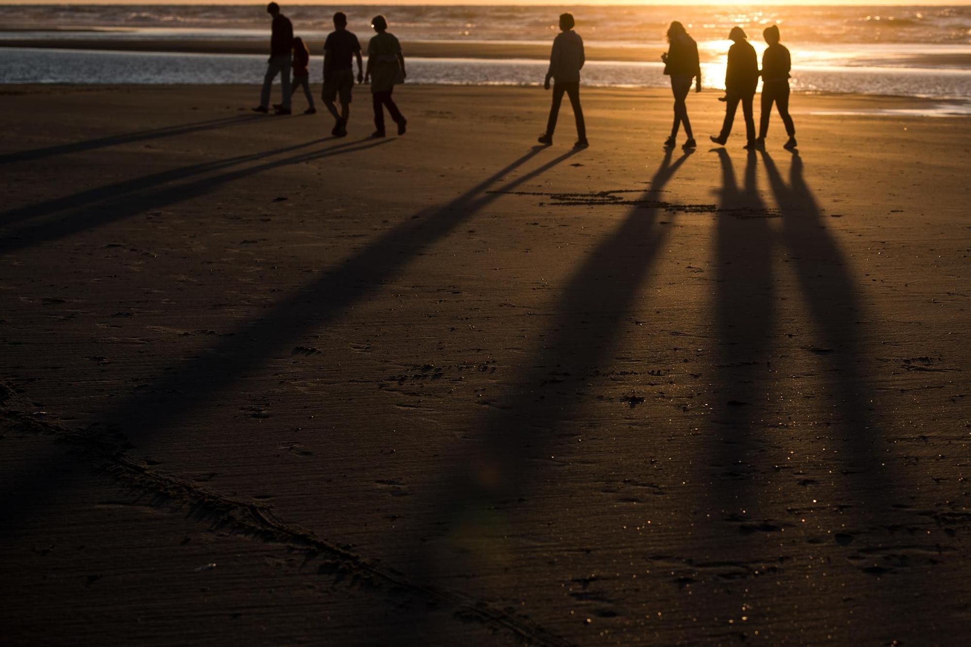 Spaziergänger bei Sonnenuntergang am Strand