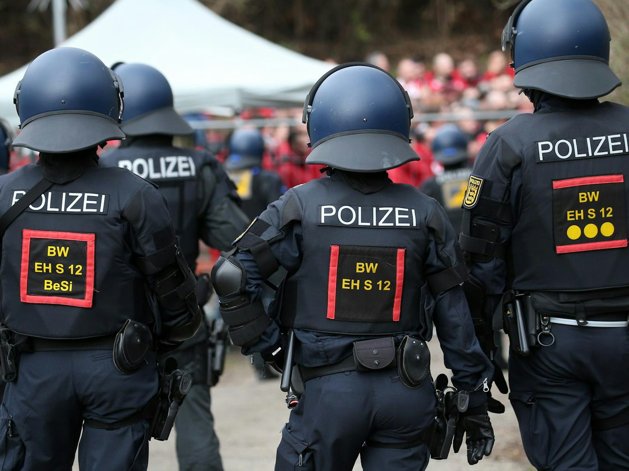 Polizisten stehen Fußballfans gegenüber.