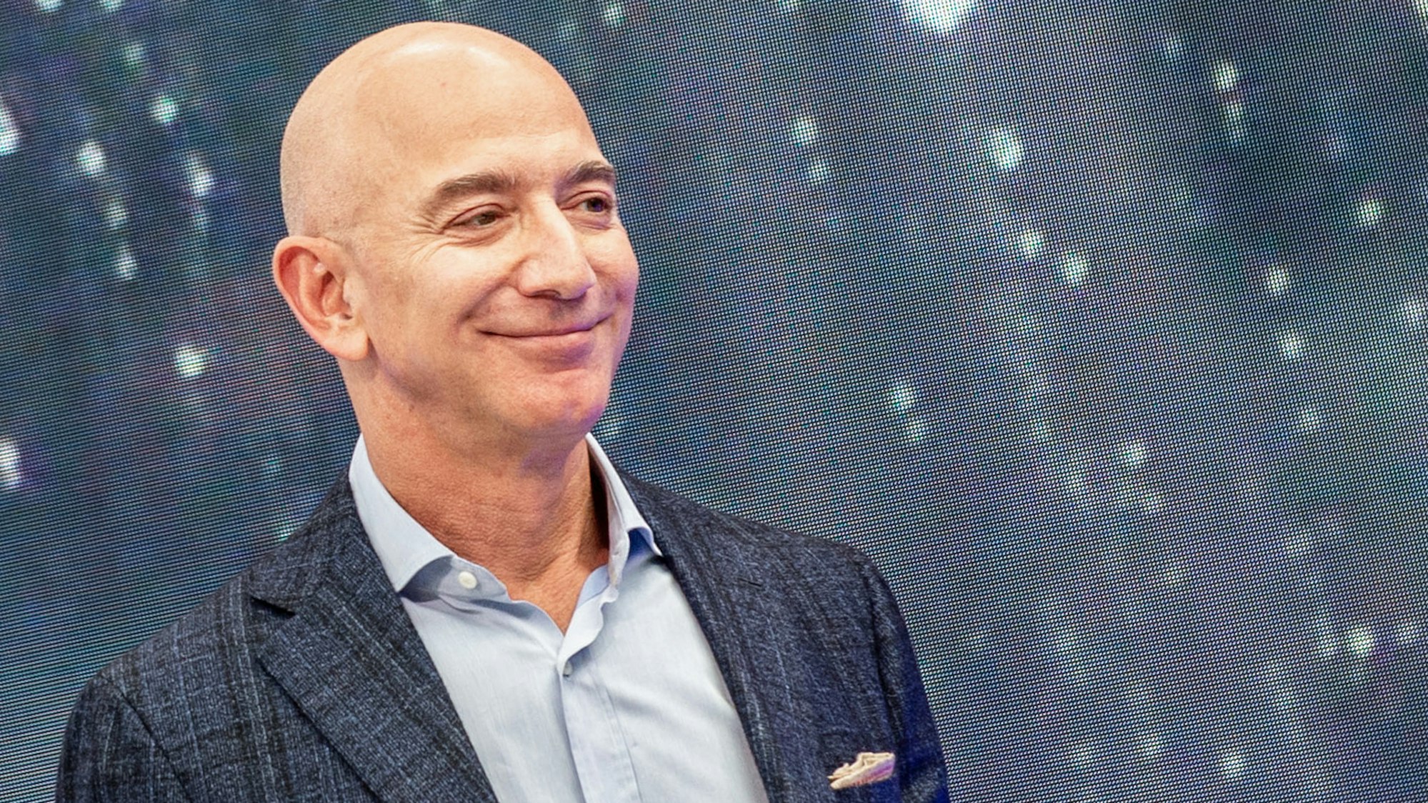 Das undatierte Foto zeigt den Amazon-Gründer Jeff Bezos in dunkler Anzugjacke und hellem Hemd. Er lächelt.
