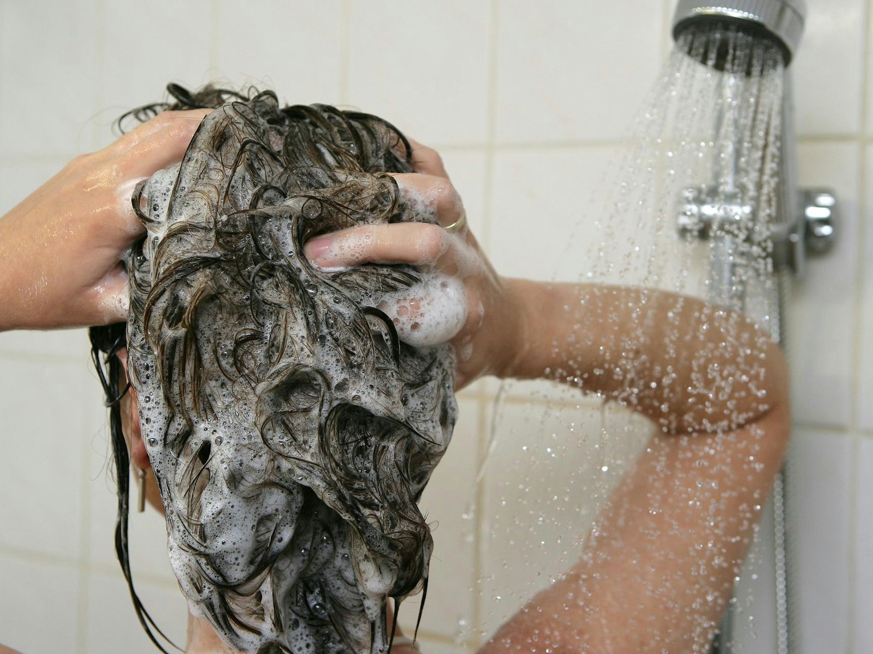 Eine Frau steht unter der Dusche und wäscht sich die Haare.