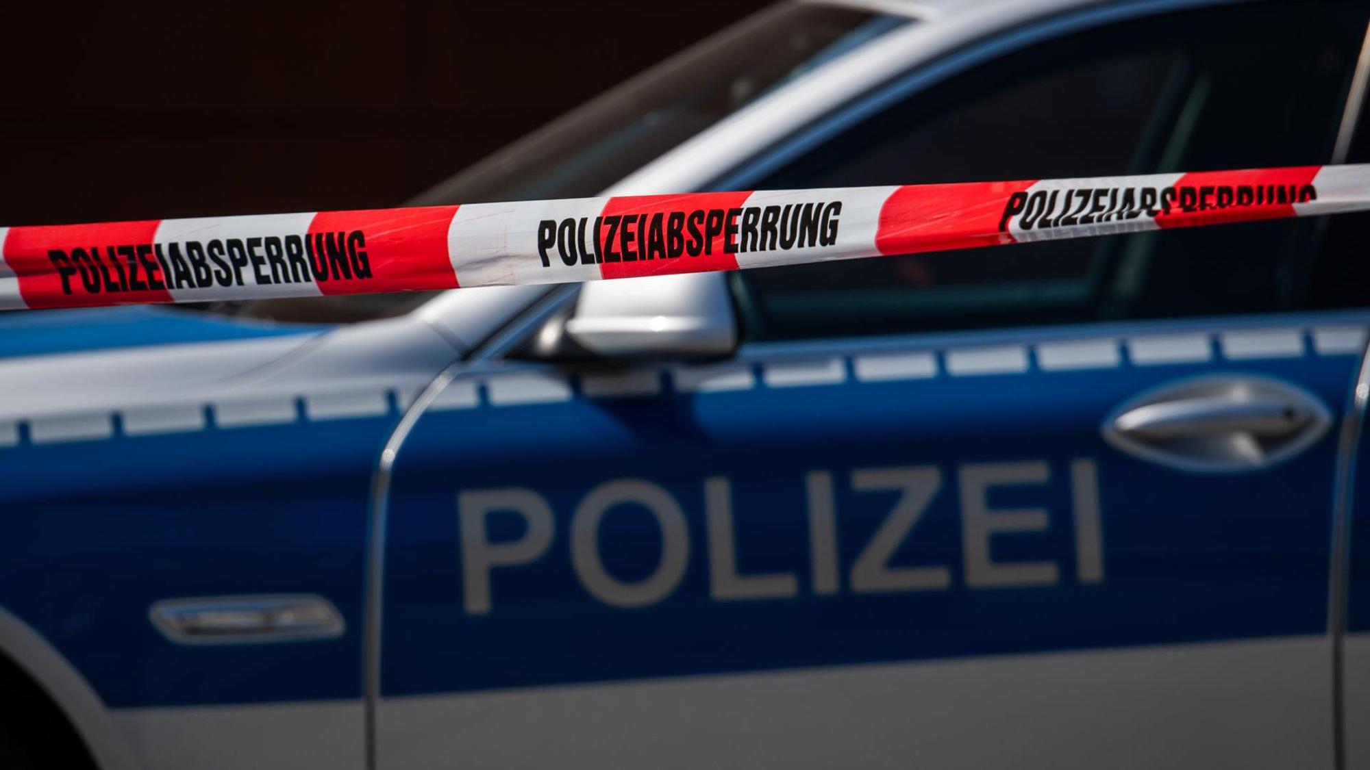 Ein Polizeiauto steht hinter einer Polizeiabsperrung.