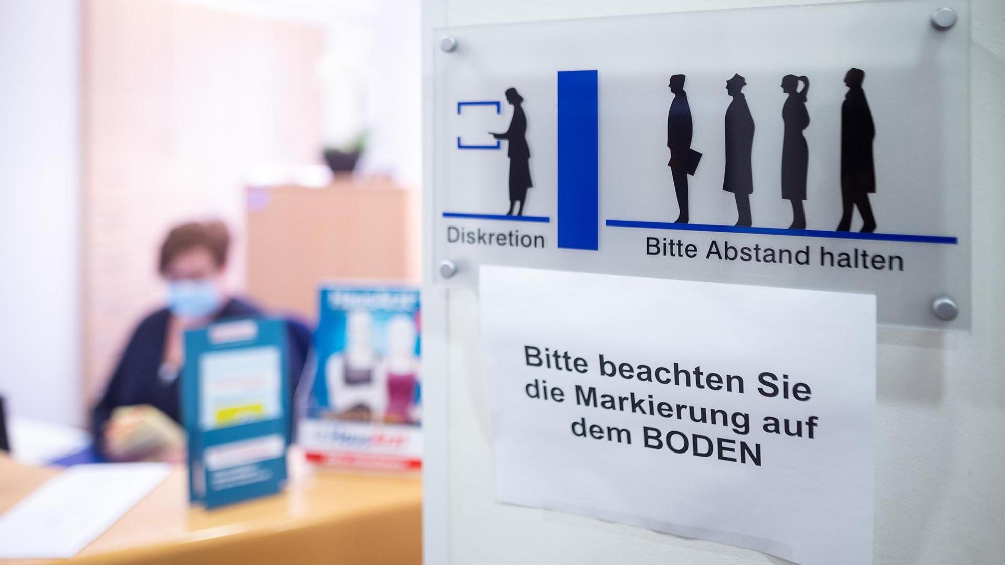 Eingangsbereich einer Arztpraxis in NRW. Eine Praxis-Mitarbeiterin sitzt an der Anmeldung.