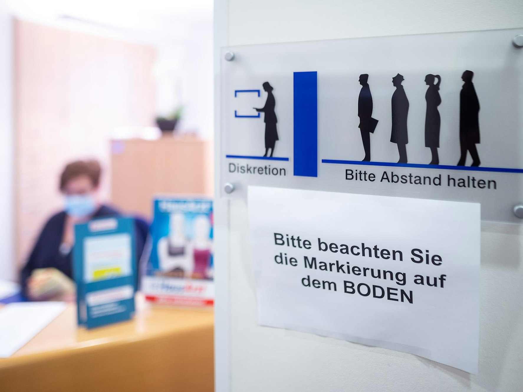 Frau sitzt an einer Anmeldung einer Arztpraxis in NRW.