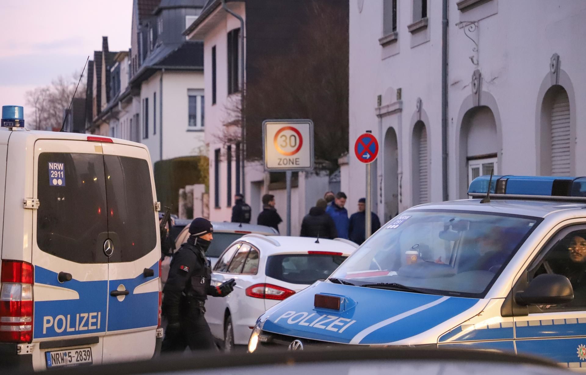 Polizeifahrzeuge stehen vor einem Haus.