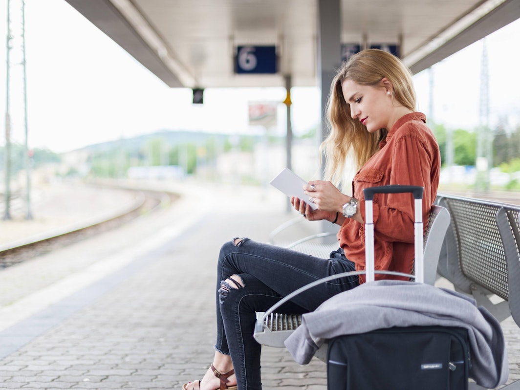 Frau am Bahnsteig mit Handy