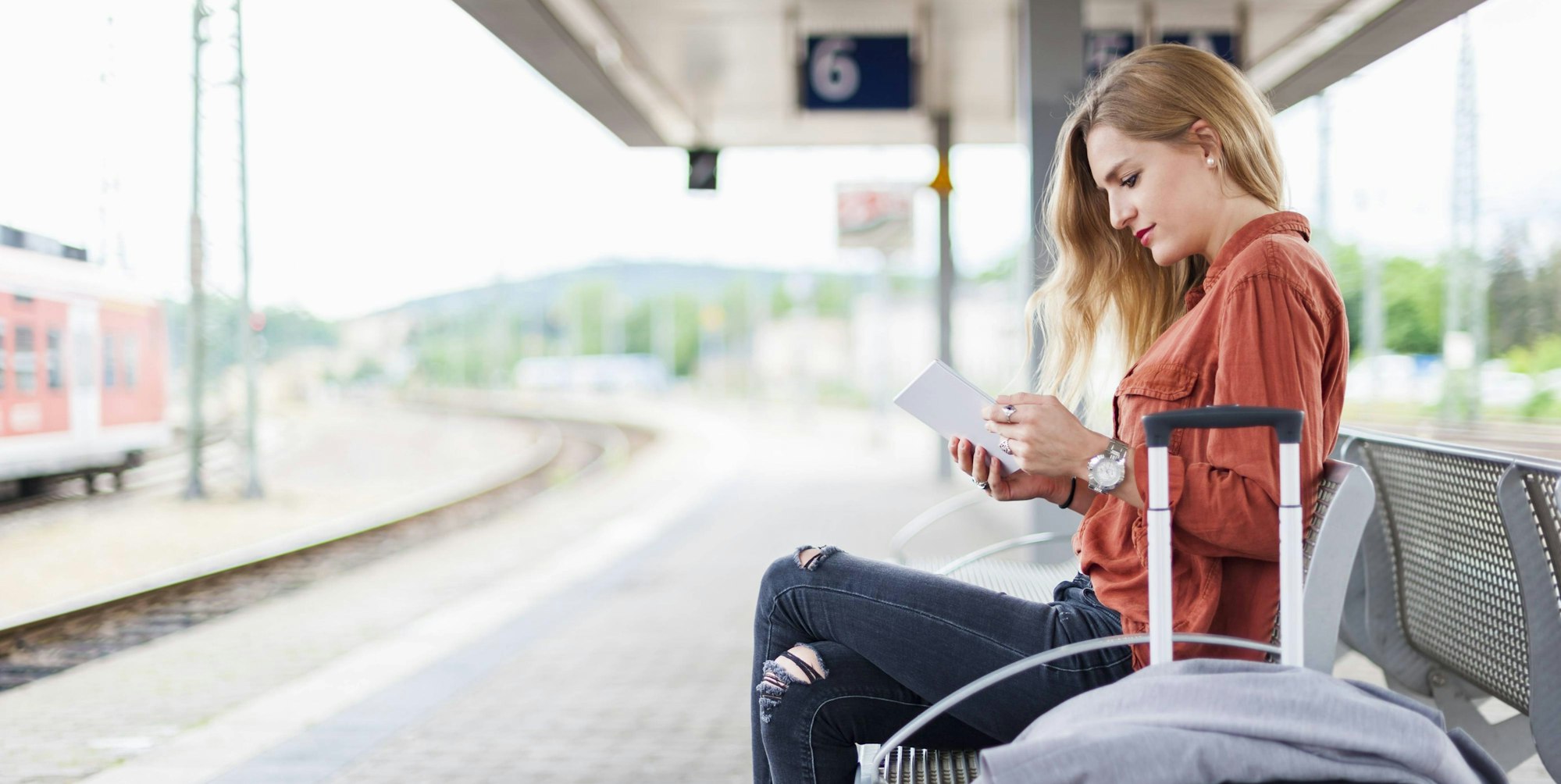 Frau am Bahnsteig mit Handy