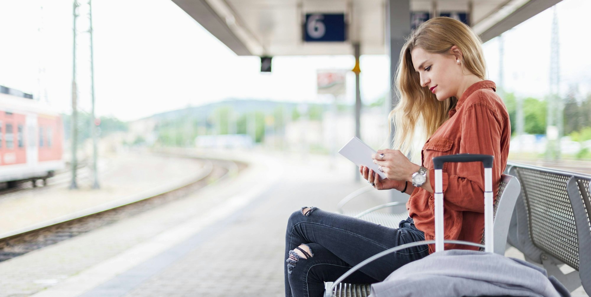 Frau am Bahnsteig mit Handy