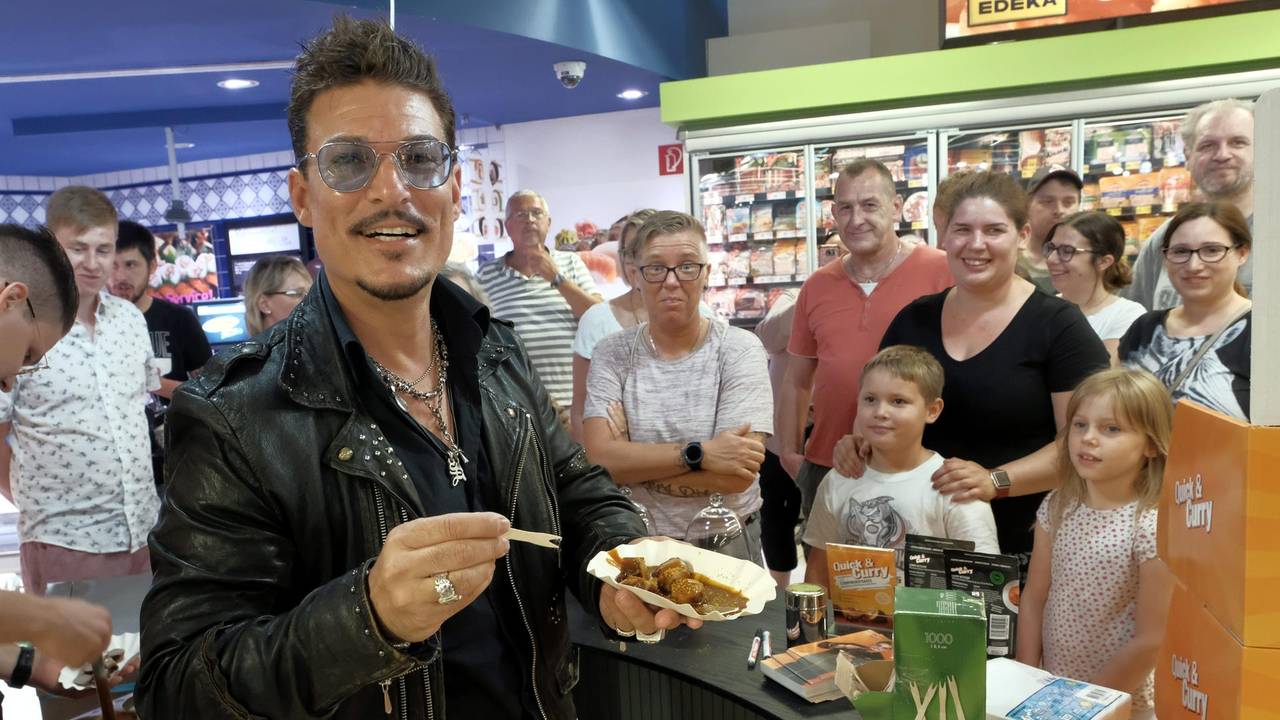 Chris Töpperwien verteilt Currywurst in einem Kölner Supermarkt.