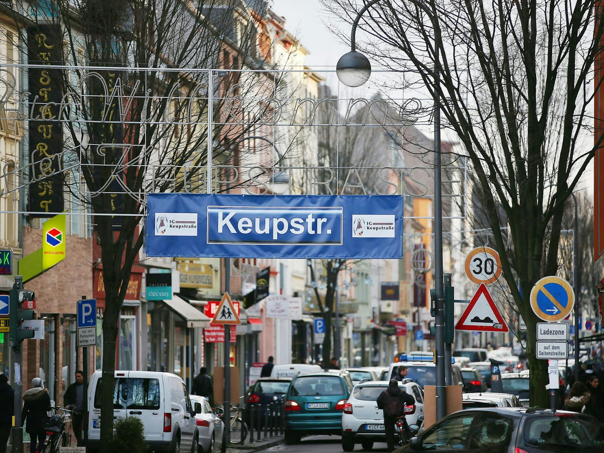 Über einer Straße hängt ein Plakat mit der Aufschrift Keupstraße.