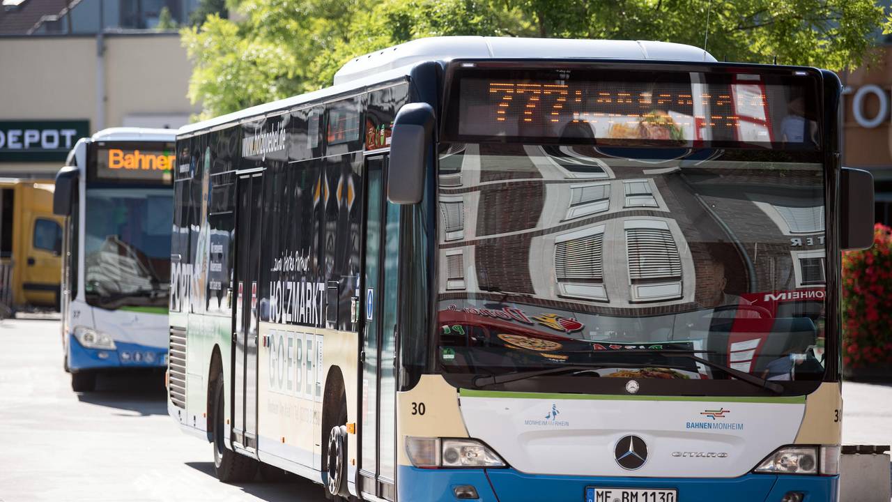 Zwei Busse stehen hintereinander an einem Busbahnhof.
