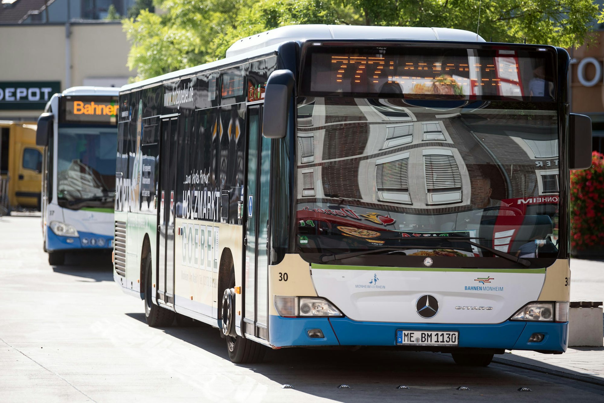 Zwei Busse stehen hintereinander an einem Busbahnhof.