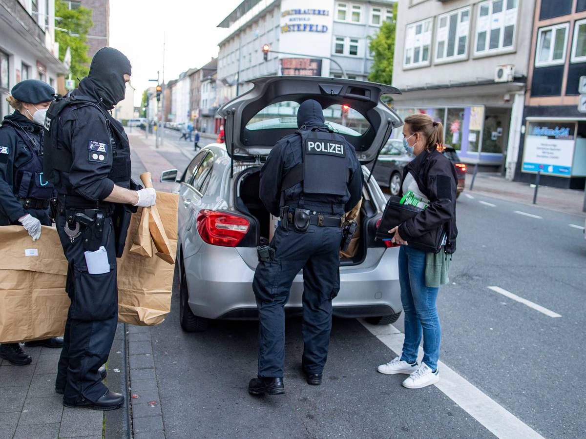 Polizisten bringen Tüten mit Beweismaterial zu einem Auto.