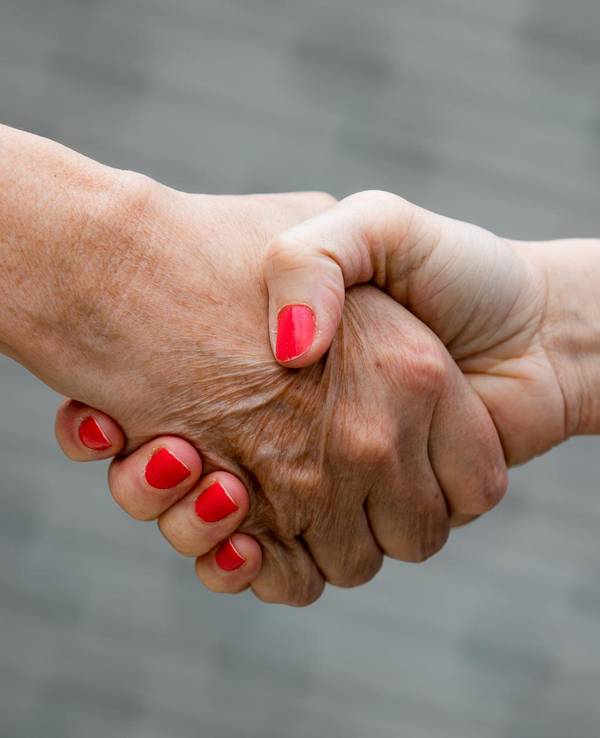 Zwei Menschen geben sich die Hand.