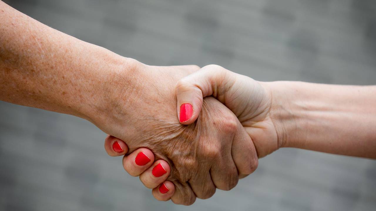 Zwei Menschen geben sich die Hand.