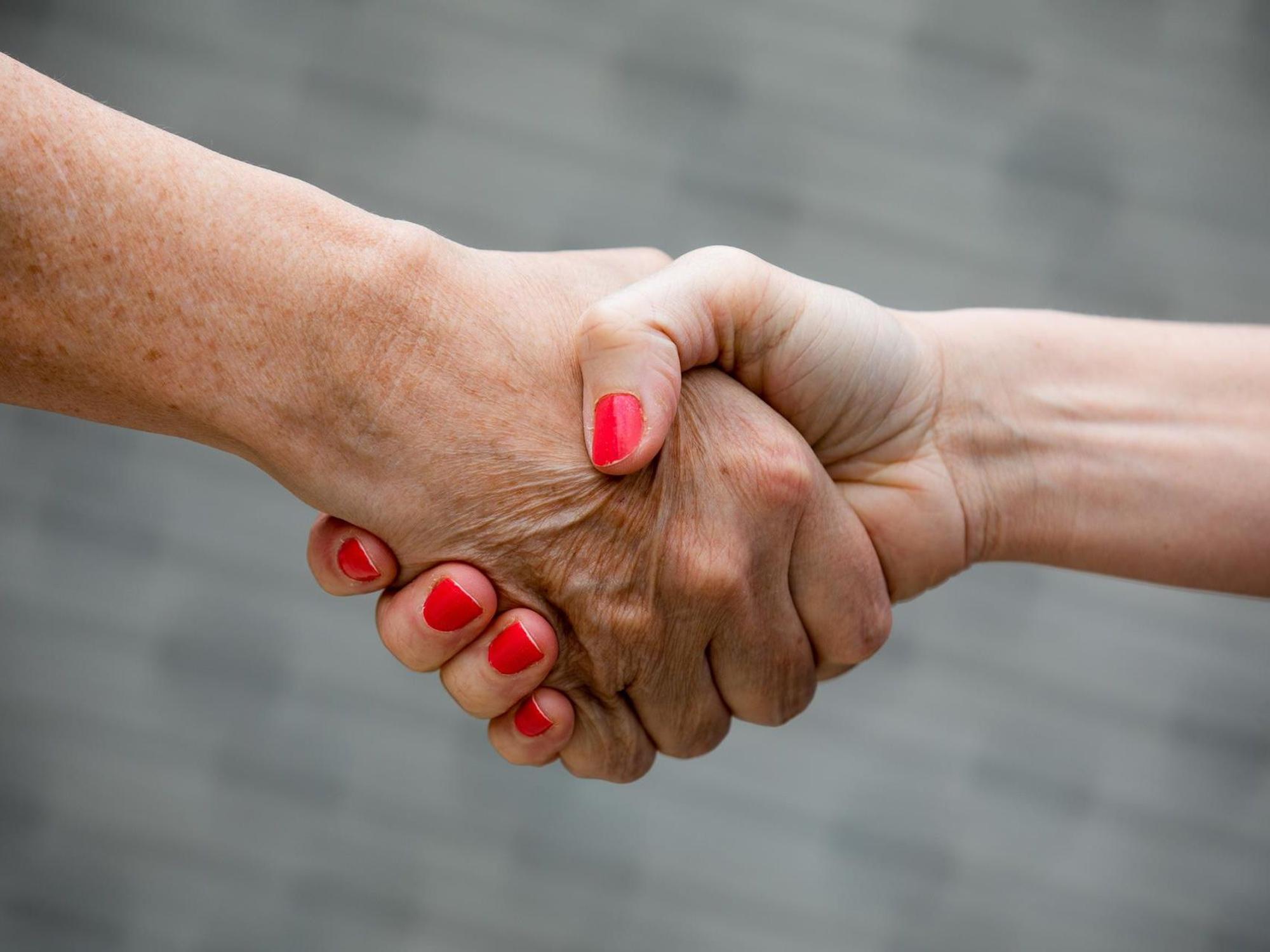 Zwei Menschen geben sich die Hand.