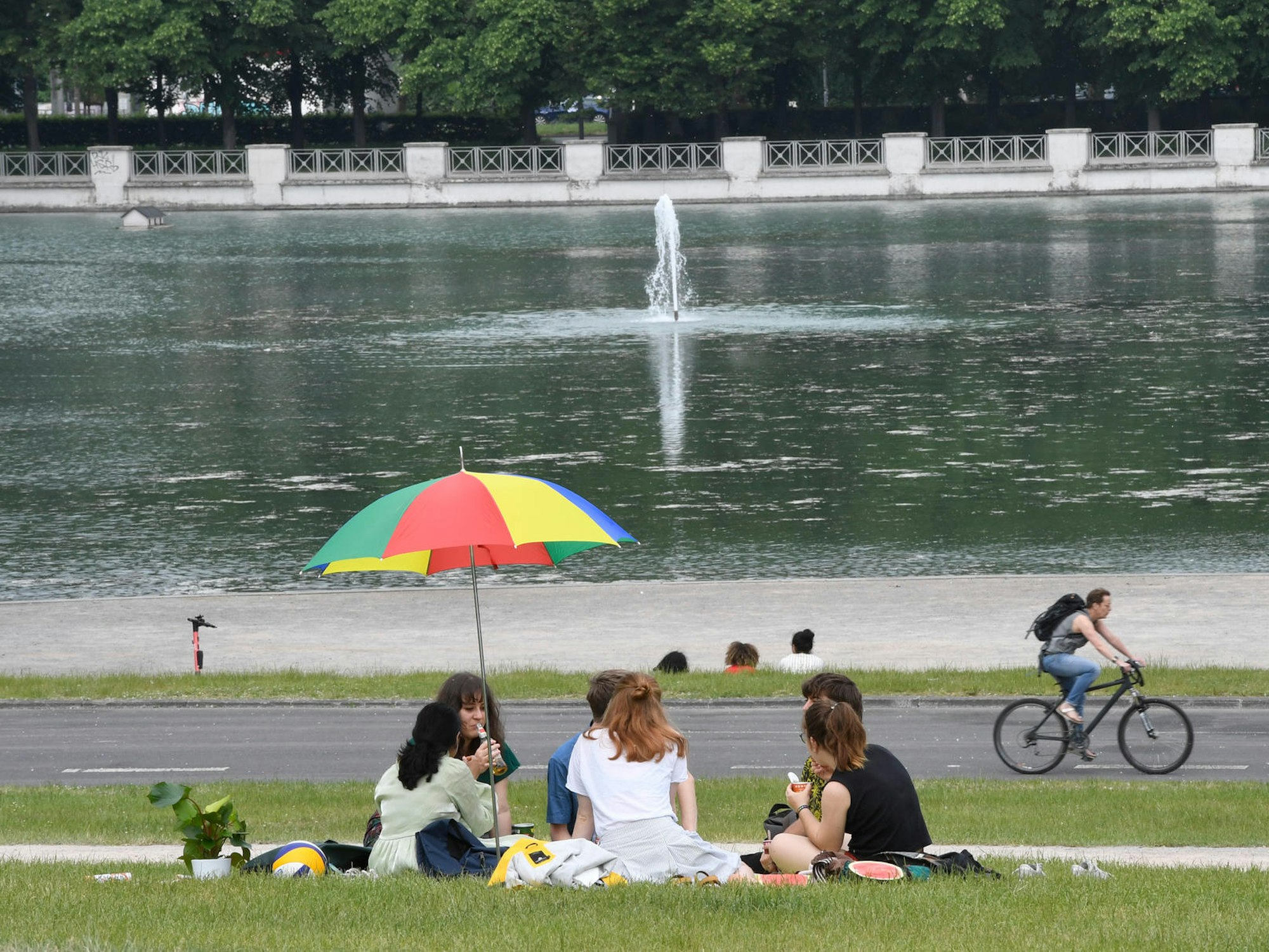Mehrere Frauen sitzen am Aachener Weiher auf der Wiese unter einem Sonnenschirm.